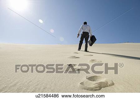 Businessman Walking Uphill With Briefcase in the Desert View Large Photo Image Stock Photograph - Businessman Walking Uphill With Briefcase in the Desert. Fotosearch