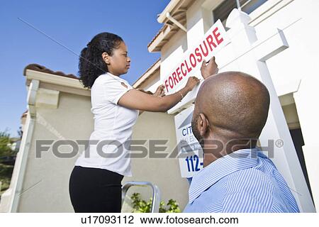Couple putting up notice outside house View Large Photo Image Stock Image - Couple putting up notice outside house. Fotosearch