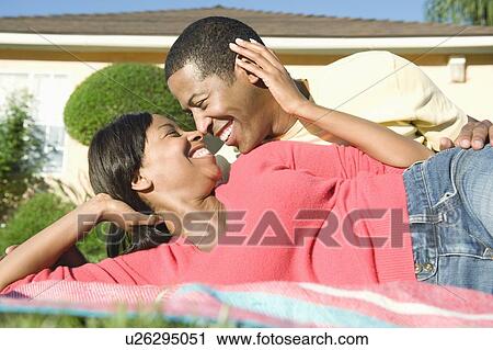 Stock Image - Couple reclining on grass. Fotosearch
