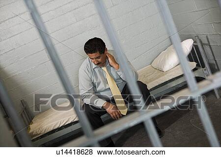Stock Photo - Criminal sitting on bed in jail. Fotosearch