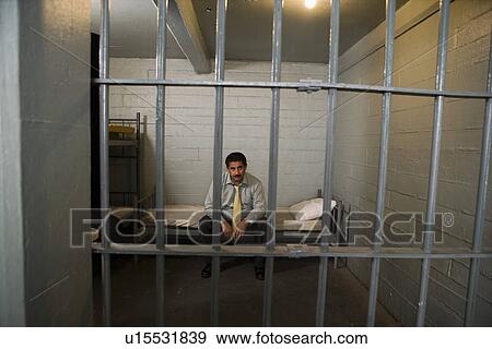 Stock Photo - Criminal sitting on bed in jail. Fotosearch