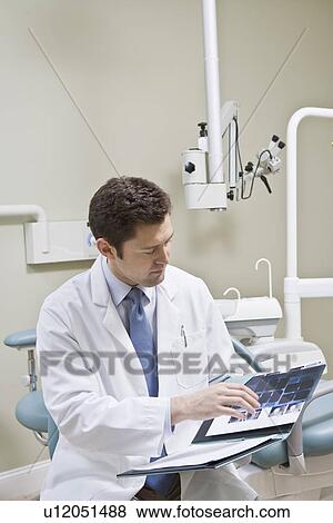 Stock Photo - Dentist leafing through medical record. Fotosearch