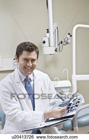 Dentist leafing through medical record View Large Photo Image Stock Photograph - Dentist leafing through medical record. Fotosearch