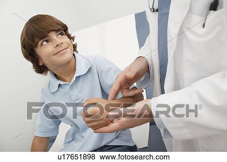 Doctor checking boys pulse View Large Photo Image Stock Photo - Doctor checking boys pulse. Fotosearch