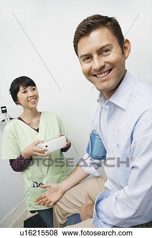 Stock Photo - Doctor checking male patients blood pressure in hospital. Fotosearch