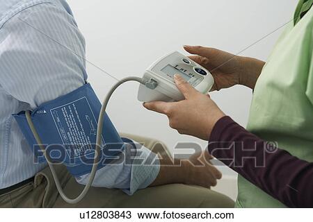 Stock Image - Doctor checking patients blood pressure, close-up. Fotosearch