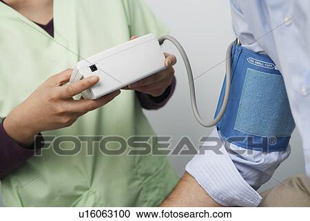 Stock Image - Doctor checking patients blood pressure, close-up. Fotosearch
