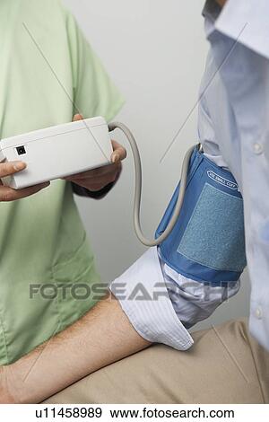 Doctor checking patients blood pressure, close-up View Large Photo Image Stock Photo - Doctor checking patients blood pressure, close-up. Fotosearch