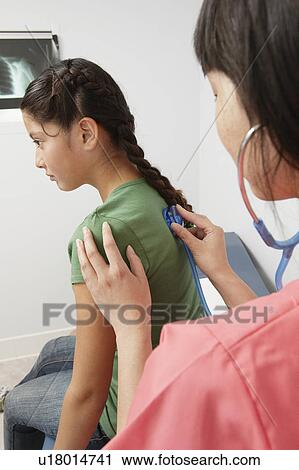Stock Image - Doctor examining girl using stethoscope in hospital. Fotosearch