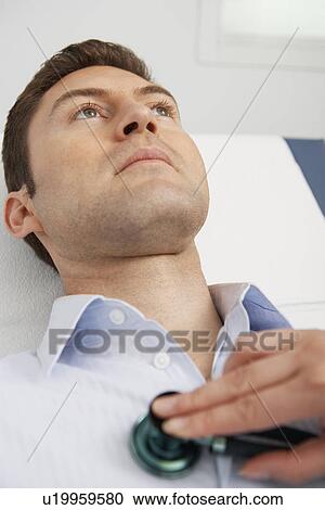 Stock Image - Doctor examining male patient using stethoscope, close-up. Fotosearch