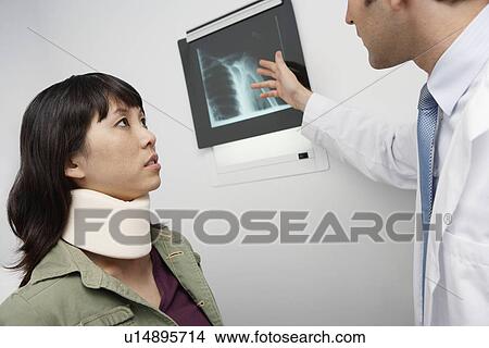 Doctor examining x-ray with female patient, in hospital View Large Photo Image Picture - Doctor examining x-ray with female patient, in hospital. Fotosearch