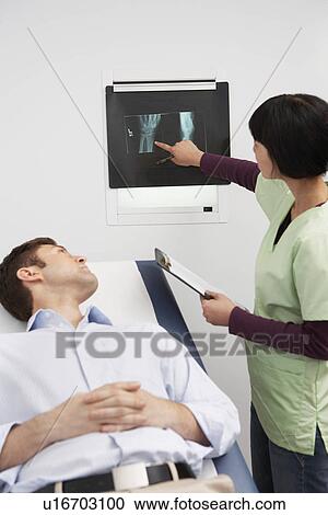 Doctor examining x-ray with male patient in hospital View Large Photo Image Stock Image - Doctor examining x-ray with male patient in hospital. Fotosearch