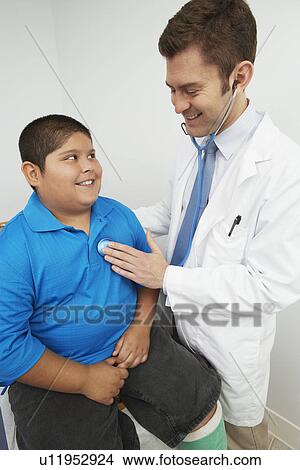 Picture - Doctor listning to boy's heartbeat. Fotosearch