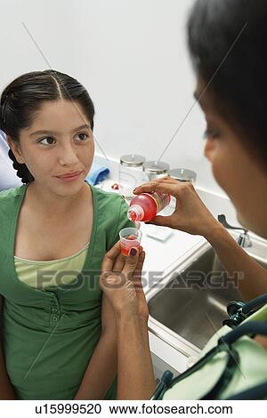 Stock Image - Doctor pouring medicine for girl. Fotosearch