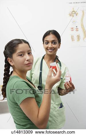 Stock Photo - Doctor with girl holding medicine in Liquid Measure. Fotosearch