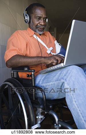 Elderly man in wheelchair listening to music and using laptop View Large Photo Image Stock Photo - Elderly man in wheelchair listening to music and using laptop. Fotosearch