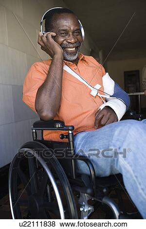 Stock Photo - Elderly man in wheelchair listening to music. Fotosearch
