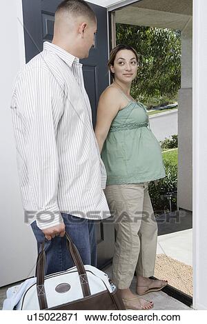 Stock Image - Expectant couple exiting house. Fotosearch