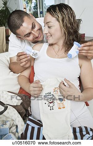Expectant couple with baby clothes View Large Photo Image Stock Image - Expectant couple with baby clothes. Fotosearch