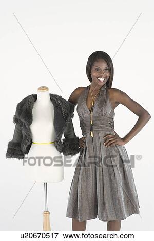 Stock Photo - Fashion model stands beside tailor's dummy with fake fur bolero jacket. Fotosearch