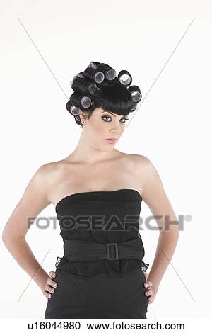 Stock Image - Fashion model stands with hands on hips in rollers. Fotosearch