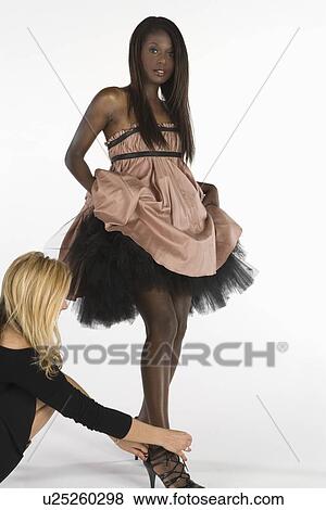 Stock Photo - Fashion stylists adjusts models footwear. Fotosearch