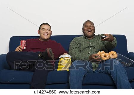 Father and son (16-17) watching TV and eating View Large Photo Image Stock Image - Father and son (16-17) watching TV and eating. Fotosearch
