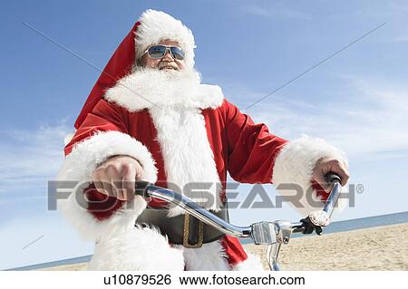 Stock Photograph - Father Christmas cycles along beach front. Fotosearch