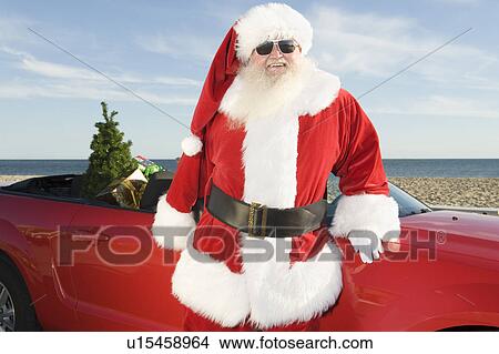 Father Christmas stands by red convertible with Christmas tree View Large Photo Image Picture - Father Christmas stands by red convertible with Christmas tree. Fotosearch