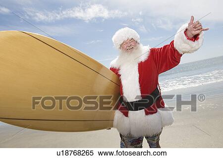 Father Christmas stands with a surfboard at the beach View Large Photo Image Stock Photography - Father Christmas stands with a surfboard at the beach. Fotosearch