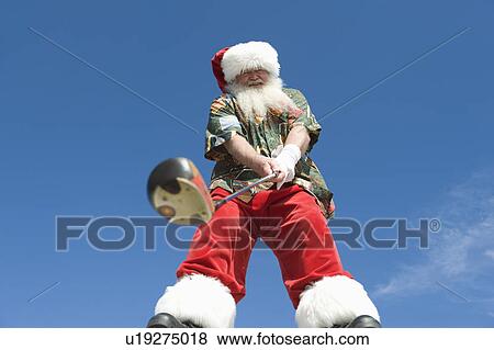 Stock Photo - Father Christmas stands with gold club. Fotosearch