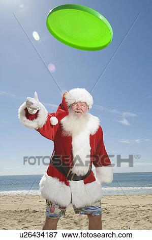 Stock Photo - Father Christmas throws a green fisbee. Fotosearch