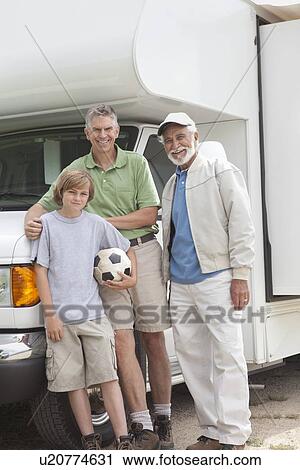 Stock Image - Father, son and grandson stand with RV home. Fotosearch