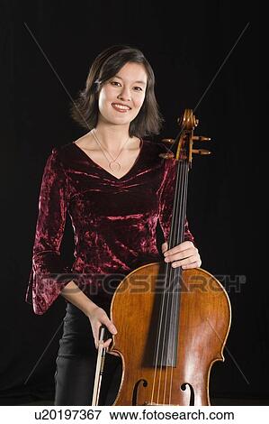 Stock Photo - Female cellist stands with cello, portrait. Fotosearch