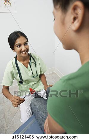 Stock Photography - Female doctor examining girl with reflex hammer. Fotosearch