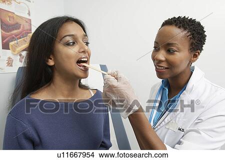 Picture - Female doctor examining patient's throat. Fotosearch