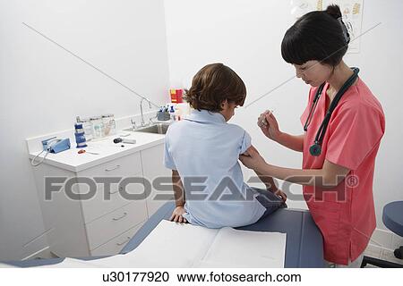 Stock Image - Female doctor giving boy injection. Fotosearch