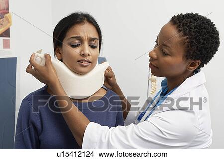 Picture - Female doctor puting brace on patient's neck. Fotosearch