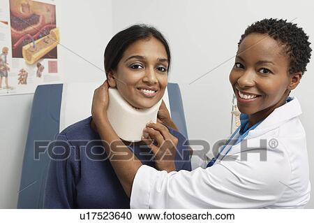 Stock Image - Female doctor puting brace on patient's neck. Fotosearch