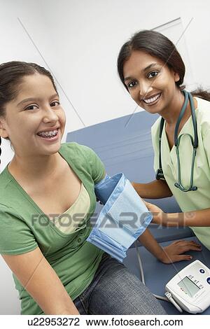 Female doctor taking girls blood pressure View Large Photo Image Stock Image - Female doctor taking girls blood pressure. Fotosearch