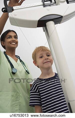 Female doctor weighting young patient View Large Photo Image Stock Image - Female doctor weighting young patient. Fotosearch