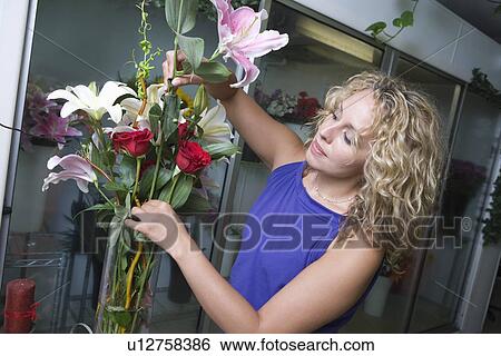Female florist arranging flowers in vase View Large Photo Image Stock Photograph - Female florist arranging flowers in vase. Fotosearch