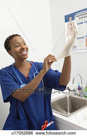 Female nurse putting on gloves in hospital View Large Photo Image Stock Photograph - Female nurse putting on gloves in hospital. Fotosearch