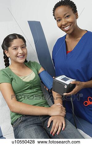 Female nurse taking girls blood pressure in hospital, portrait View Large Photo Image Stock Photo - Female nurse taking girls blood pressure in hospital, portrait. Fotosearch