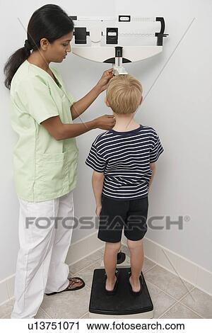 Stock Image - Female nurse weighting young patient. Fotosearch