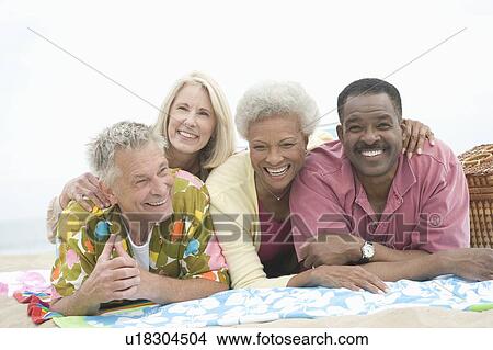 Four senior friends lie on their stomachs on the beach View Large Photo Image Picture - Four senior friends lie on their stomachs on the beach. Fotosearch