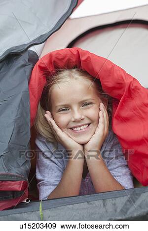 Stock Photo - Girl under sleeping bag smiles from tent. Fotosearch