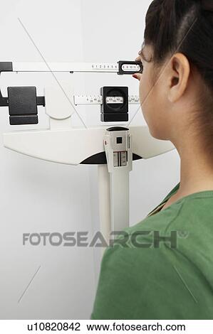 Stock Image - Girl using measuring scales in hospital. Fotosearch