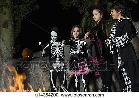 Girls and boys (7-9) wearing Halloween costumes, cooking marshmallows on campfire View Large Photo Image Stock Image - Girls and boys (7-9) wearing Halloween costumes, cooking marshmallows on campfire. Fotosearch
