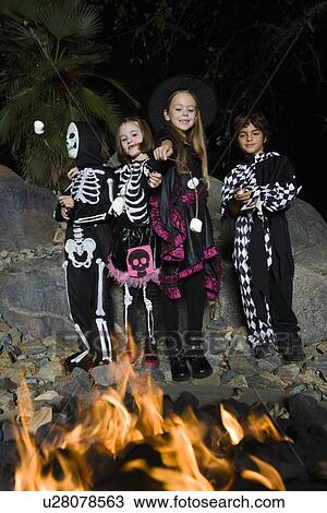 Girls and boys (7-9) wearing Halloween costumes, cooking marshmallows on campfire View Large Photo Image Stock Image - Girls and boys (7-9) wearing Halloween costumes, cooking marshmallows on campfire. Fotosearch